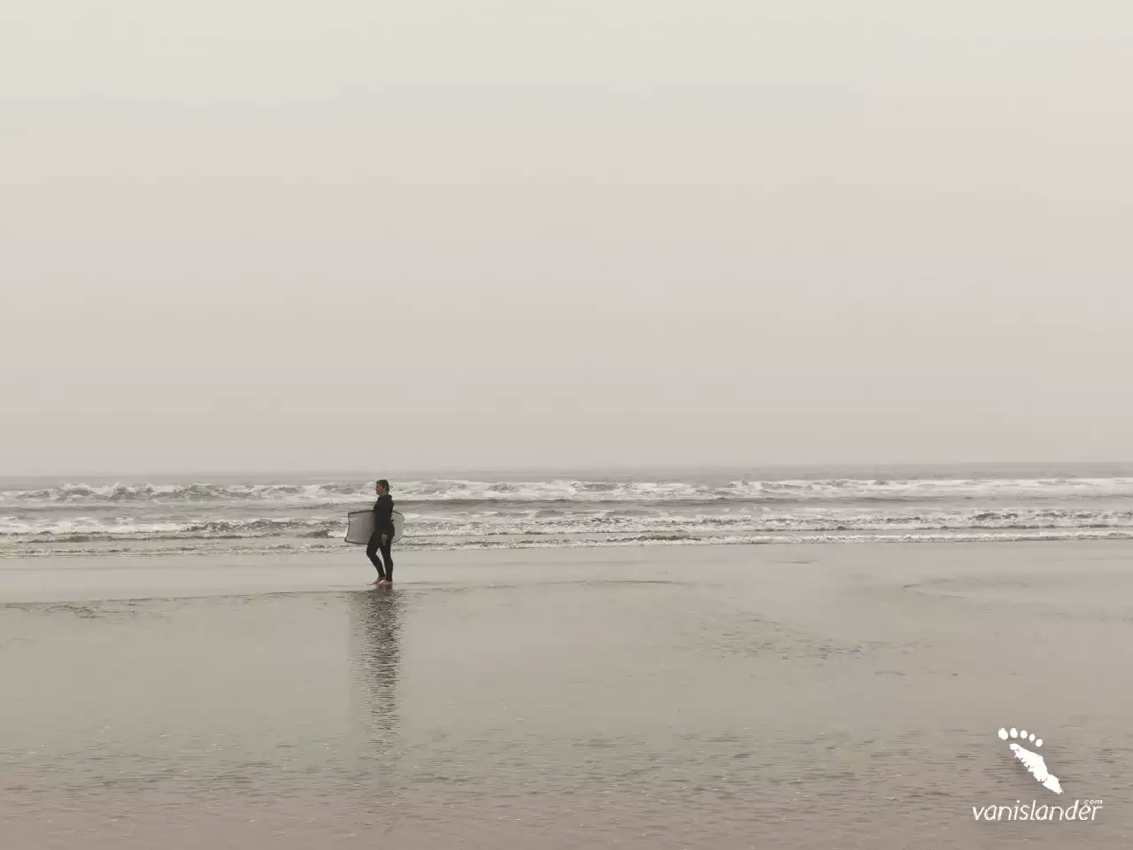 Surfer walking by the ocean on Long Beach,  Vancouver Island